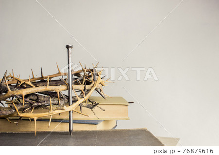 A thorn crown with nails and Holy Bible on a wooden table over the light background.  76879616