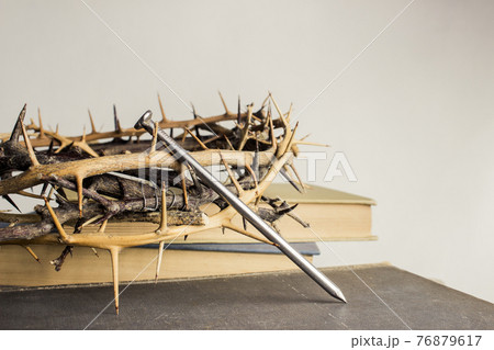 A thorn crown with nails and Holy Bible on a wooden table over the light background.  76879617