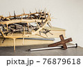 A thorn crown with nails and Holy Bible on a wooden table over the light background.  76879618
