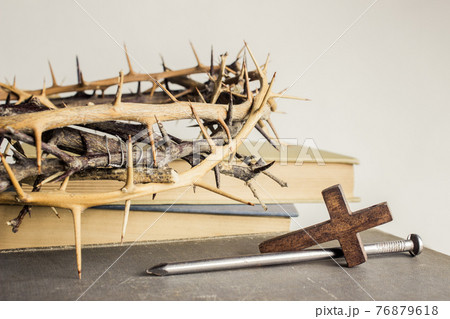 A thorn crown with nails and Holy Bible on a wooden table over the light background.  76879618