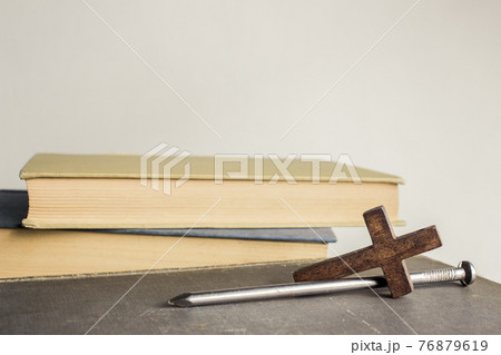 A cross with nail with bible over a light background.  76879619