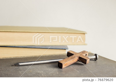 A cross with nail with bible over a light background.  76879620