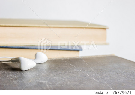 An earphone with books over the light background. 76879621