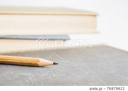 A sharp pencil over books with a light background.  76879622