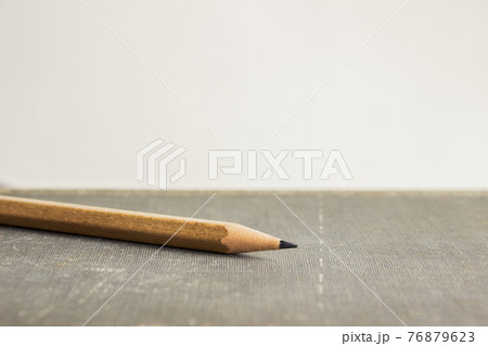 A sharp pencil over book with a light background.  76879623
