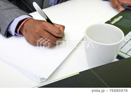 Close up of Indian mans hands writing on paper. 76880976