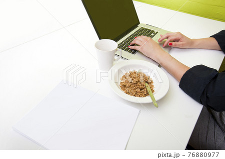 Close up of womans hands typing on laptop with mug in foreground 76880977
