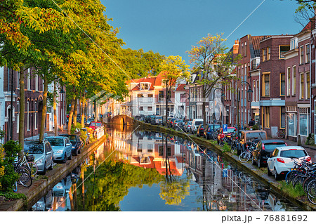 Delt canal with old houses and cars parked along on sunset 76881692