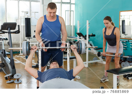 Man doing bench press with help of coach Man doing bench press with help of coach 76885869