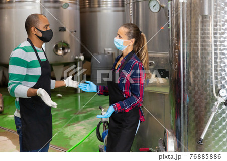 Communication of winery workers in protective masks in production shop Communication of winery workers in protective masks in production shop 76885886