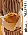 Baker holding loaf of homemade bread 76887684