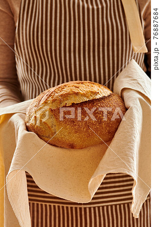 Baker holding loaf of homemade bread Baker holding loaf of homemade bread 76887684