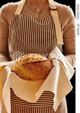 Baker holding loaf of homemade bread 76887685