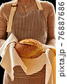 Baker holding loaf of homemade bread 76887686
