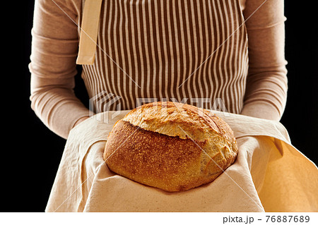 Baker holding loaf of homemade bread 76887689