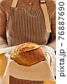 Baker holding loaf of homemade bread 76887690