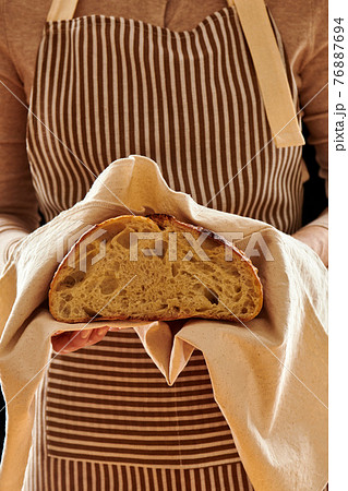 Baker holding loaf of homemade bread Baker holding loaf of homemade bread 76887694