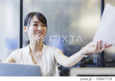 デスクで書類を受け渡す女性 ビジネスシーン 76887728