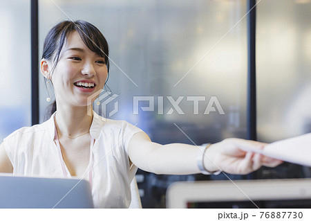 デスクで書類を受け渡す女性 ビジネスシーン 76887730