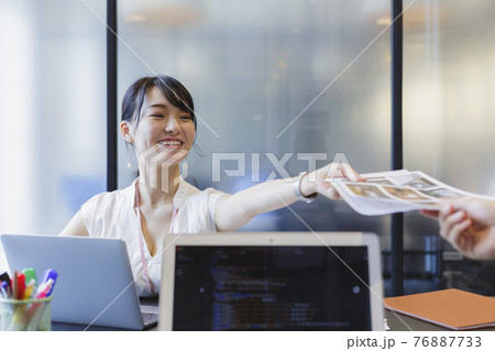 デスクで書類を受け渡す女性 ビジネスシーン 76887733