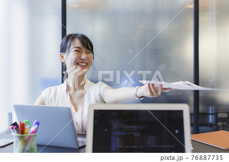 デスクで書類を受け渡す女性 ビジネスシーン 76887735