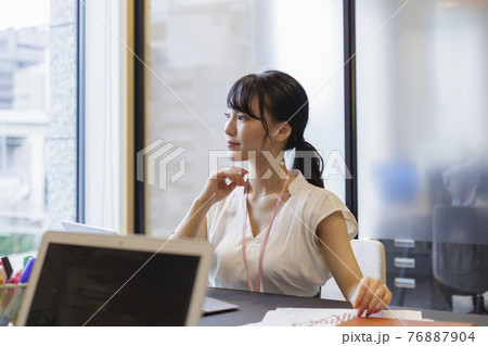 オフィスのデスクで考え事をする女性 オフィスのデスクで考え事をする女性 76887904
