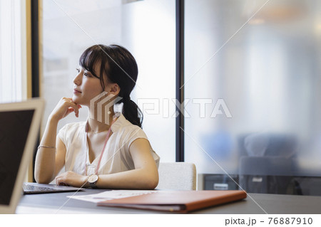 オフィスのデスクで考え事をする女性 オフィスのデスクで考え事をする女性 76887910
