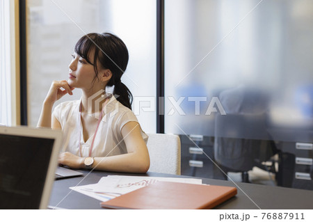 オフィスのデスクで考え事をする女性 オフィスのデスクで考え事をする女性 76887911