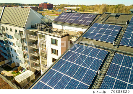 Aerial view of solar photovoltaic panels on a roof top of residential building block for producing clean electric energy. Autonomous housing concept. Aerial view of solar photovoltaic panels on a roof top of residential building block for producing clean electric energy. Autonomous housing concept. 76888829