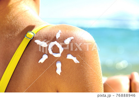 Back View of Young Woman Tanning at the Beach with Sunscreen Cream