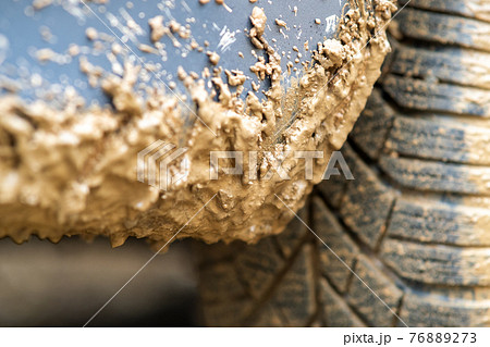 Close up of dirty car wheel with rubber tire covered with yellow mud. Close up of dirty car wheel with rubber tire covered with yellow mud. 76889273