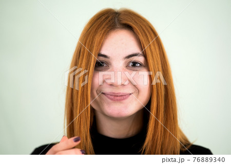 Closeup portrait of a funny redhead teenage girl with childish hairstyle isolated on white backround. 76889340