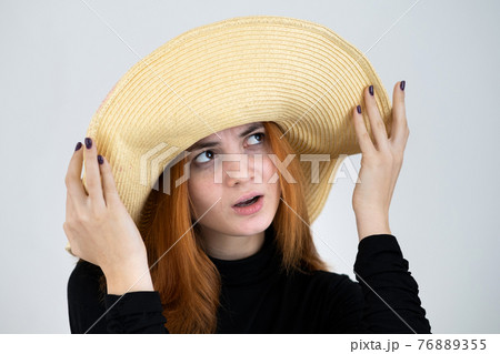 Portrait of funny redhead woman in bag yellow straw hat. 76889355