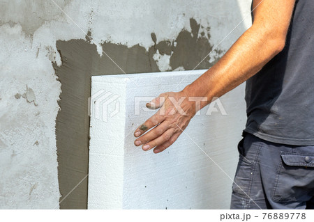 Insulation of facade wall with styrofoam sheets. Polystyrene insulation boards with glue adhesive. Insulation of facade wall with styrofoam sheets. Polystyrene insulation boards with glue adhesive. 76889778