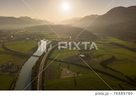 Aerial view of highway interstate road with fast moving traffic near big river in Alps mountains Aerial view of highway interstate road with fast moving traffic near big river in Alps mountains 76889780
