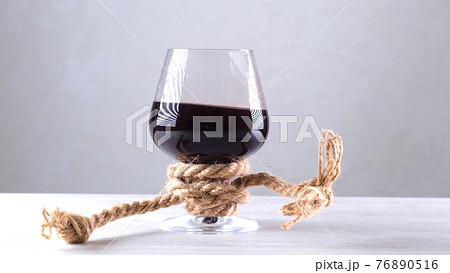 The wine glass is tied with a rope. The concept of alcohol dependence. The wine glass is tied with a rope. The concept of alcohol dependence. 76890516