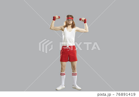 Funny smiling hipster skinny young guy doing workout with dumbbels 76891419