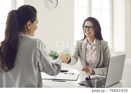 Happy young women meeting in the office, making a business deal and shaking hands 76891420