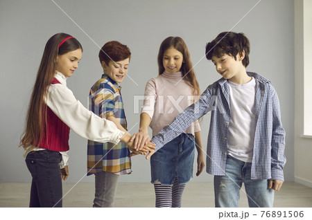 Group of children stand and join hands together studio shot on copy space Group of children stand and join hands together studio shot on copy space 76891506