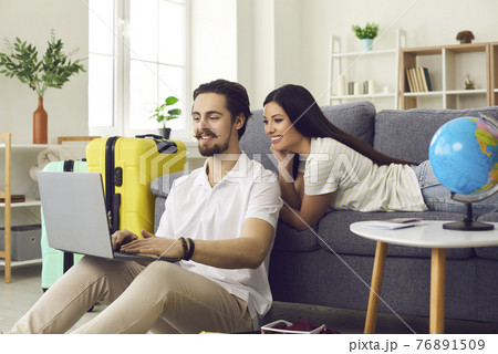 Couple is preparing for a vacation and is looking for online tours using a laptop at home. 76891509