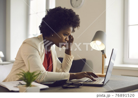 Thoughtful confused young african american businesswoman looking at laptop Thoughtful confused young african american businesswoman looking at laptop 76891520