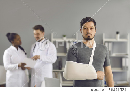 Serious man patient with broken arm wrapped on orthopedic bandage portrait 76891521