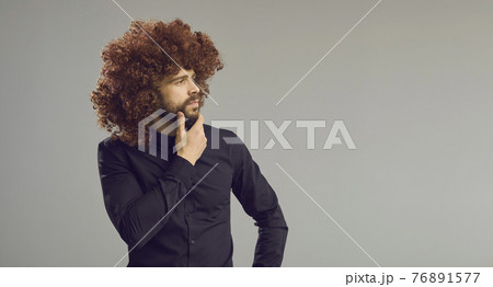 Funny intrigued man looking away at copy space standing on grey banner background 76891577