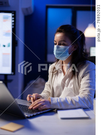 Project manager with protection face mask using professional laptop 76892031