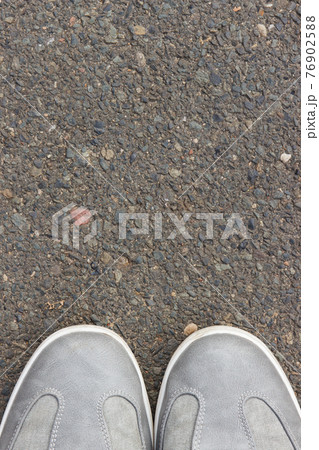Gray leather shoes on asphalt road or footpath. Male footwear. Copy space for text Gray leather shoes on asphalt road or footpath. Male footwear. Copy space for text 76902588