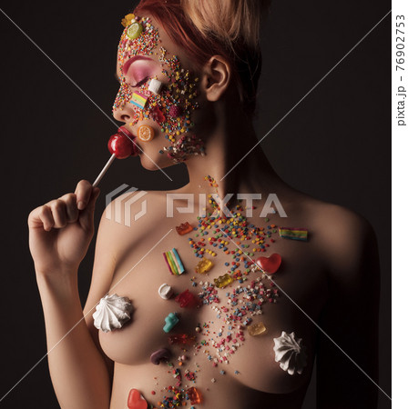 Naked woman in sweet candies licking lollipop Naked woman in sweet candies licking lollipop 76902753