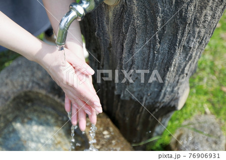 春らしい暖かい日の公園で散歩の途中で手を洗う女性 76906931