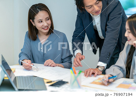 住宅の間取り図面を見ながら打ち合わせをする男女三人 建築士　ビジネスシーン 76907194