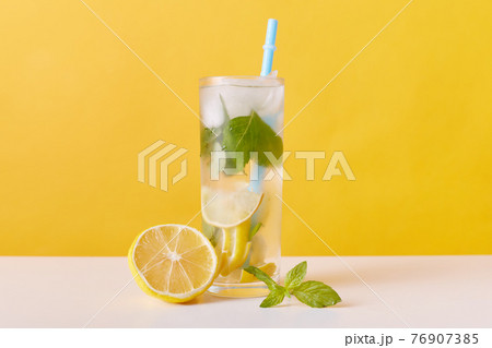 Homemade refreshing summer lemonade drink with lemon slices, mint and ice cubes, glasses with drinking straw isolated over yellow wall, detox cocktail. Homemade refreshing summer lemonade drink with lemon slices, mint and ice cubes, glasses with drinking straw isolated over yellow wall, detox cocktail. 76907385