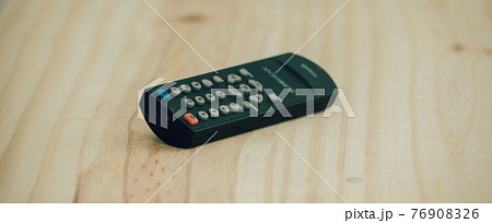 Small Remote controller lay flat on a wooden surface close up photograph. Small Remote controller lay flat on a wooden surface close up photograph. 76908326